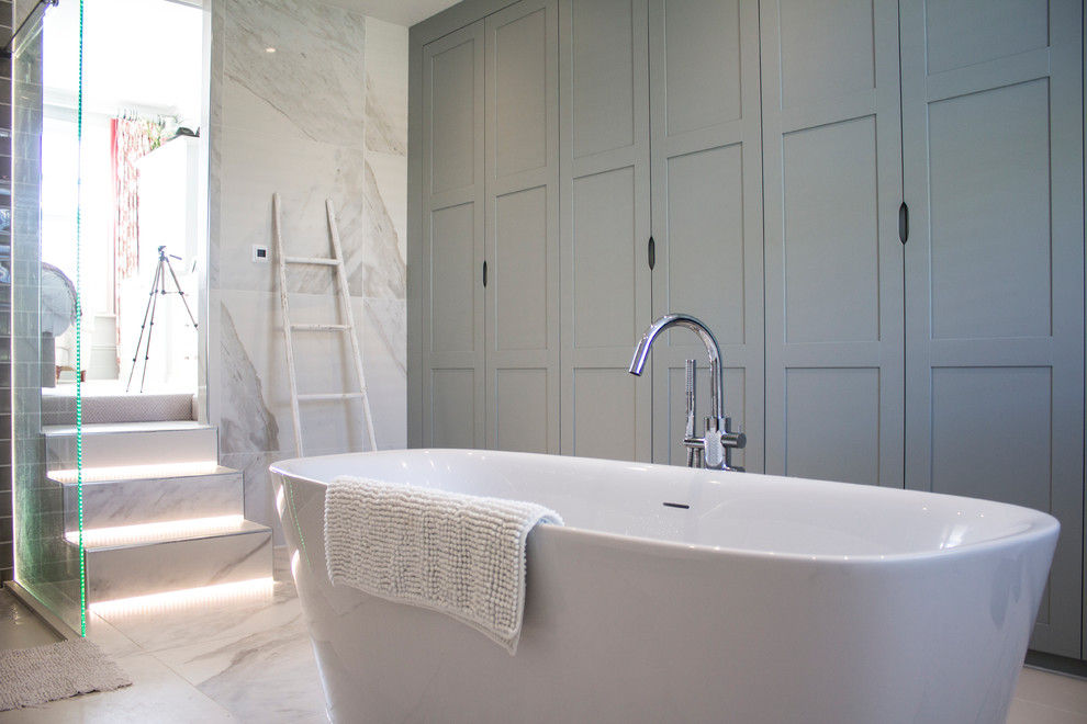 Modelo de cuarto de baño principal contemporáneo de tamaño medio con bañera exenta, ducha abierta, sanitario de pared, baldosas y/o azulejos de porcelana y baldosas y/o azulejos blancos