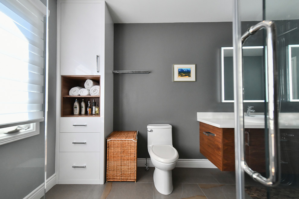 Modern inredning av ett stort vit vitt badrum med dusch, med släta luckor, skåp i mellenmörkt trä, en hörndusch, grå kakel, porslinskakel, grå väggar, betonggolv, ett fristående handfat, bänkskiva i akrylsten, grått golv och dusch med skjutdörr