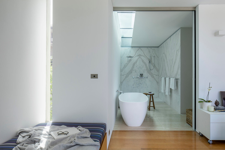 На фото: ванная комната в современном стиле с отдельно стоящей ванной, открытым душем, плиткой из листового камня, инсталляцией, белой плиткой, белыми стенами, полом из травертина, подвесной раковиной и желтым полом с