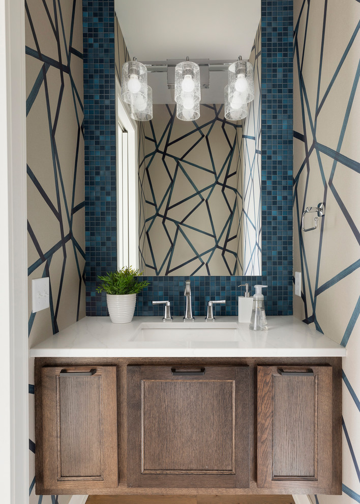 Idée de décoration pour une petite salle de bain tradition en bois brun avec un carrelage bleu, mosaïque, un mur multicolore, un sol en bois brun, un lavabo encastré, un plan de toilette en marbre, un plan de toilette blanc, un placard avec porte à panneau encastré et un sol marron.