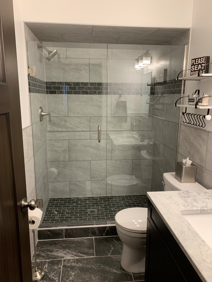 Inspiration for a mid-sized contemporary 3/4 gray tile and porcelain tile porcelain tile, black floor and single-sink alcove shower remodel in Minneapolis with shaker cabinets, dark wood cabinets, a one-piece toilet, gray walls, an undermount sink, marble countertops, a hinged shower door, gray countertops and a freestanding vanity