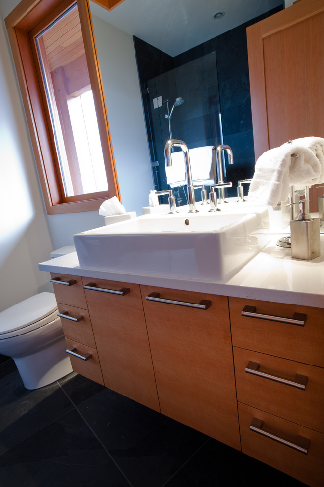 Aménagement d'une salle de bain contemporaine en bois clair avec un placard à porte plane, un plan de toilette en quartz, un carrelage noir, des dalles de pierre, un mur blanc et un sol en ardoise.