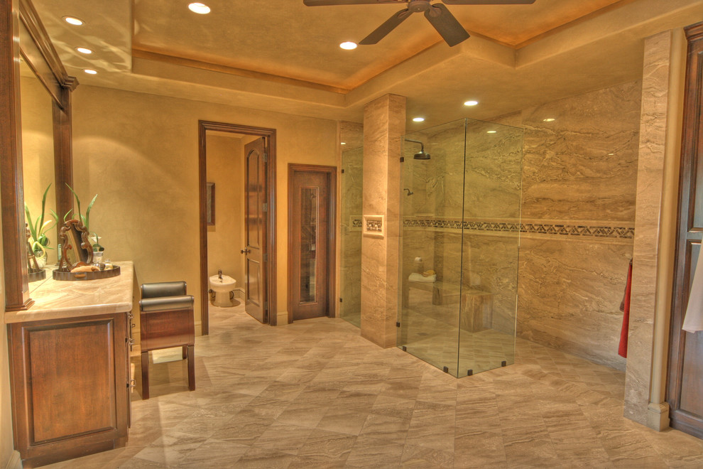 Large mediterranean ensuite bathroom in Orange County with raised-panel cabinets, dark wood cabinets, a walk-in shower, a bidet, brown tiles, stone tiles, brown walls, porcelain flooring, marble worktops, brown floors and an open shower.