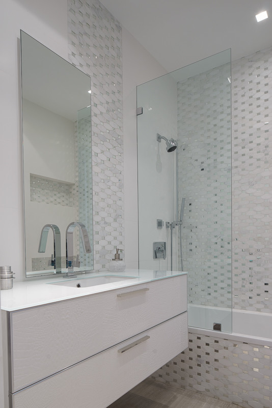 На фото: ванная комната среднего размера в стиле модернизм с плоскими фасадами, белыми фасадами, ванной в нише, душем над ванной, белыми стенами, полом из керамогранита, душевой кабиной, врезной раковиной, стеклянной столешницей, бежевым полом, душем с распашными дверями и белой столешницей с