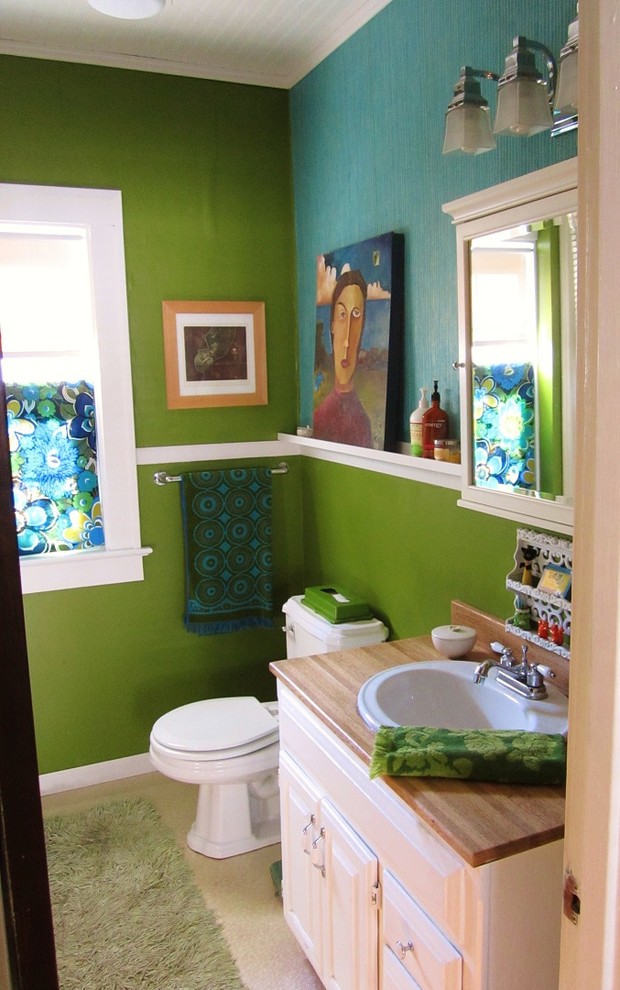 Cette photo montre une salle de bain principale éclectique avec un lavabo posé, des portes de placard blanches, un plan de toilette en bois, WC à poser, un mur vert et un sol en linoléum.