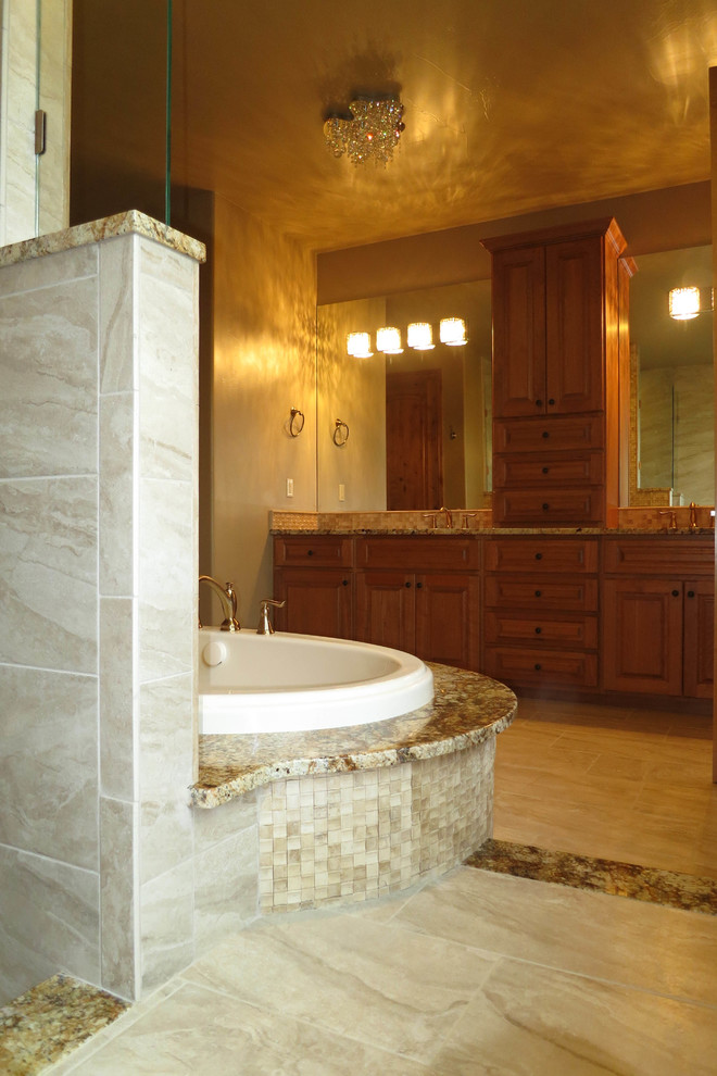 Foto di una grande stanza da bagno padronale contemporanea con lavabo da incasso, ante con bugna sagomata, ante in legno scuro, top in granito, vasca da incasso e pavimento in gres porcellanato