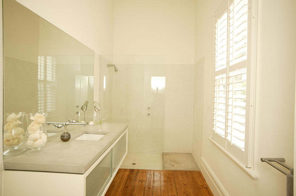 Immagine di una stanza da bagno padronale minimal con ante di vetro, ante bianche, doccia ad angolo, piastrelle bianche, piastrelle in ceramica, pareti bianche, pavimento in legno massello medio, lavabo integrato e top in quarzite