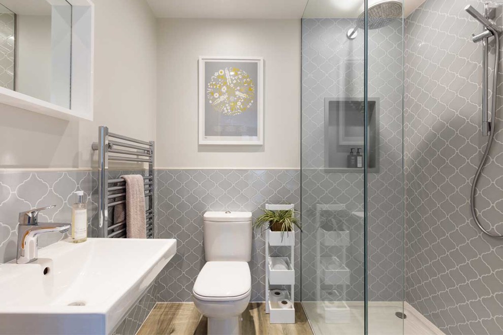 На фото: ванная комната среднего размера в современном стиле с открытым душем, раздельным унитазом, серой плиткой, бежевыми стенами, светлым паркетным полом, подвесной раковиной и бежевым полом с