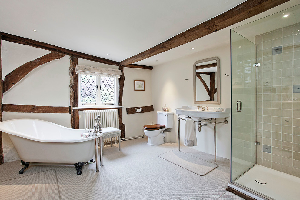 Cette image montre une salle de bain principale rustique avec une baignoire sur pieds, une douche d'angle, WC séparés, un mur beige, un lavabo suspendu, un sol beige et une cabine de douche à porte battante.