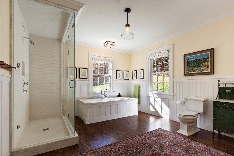 Пример оригинального дизайна: ванная комната в классическом стиле с полновстраиваемой ванной, угловым душем, раздельным унитазом, белой плиткой и желтыми стенами