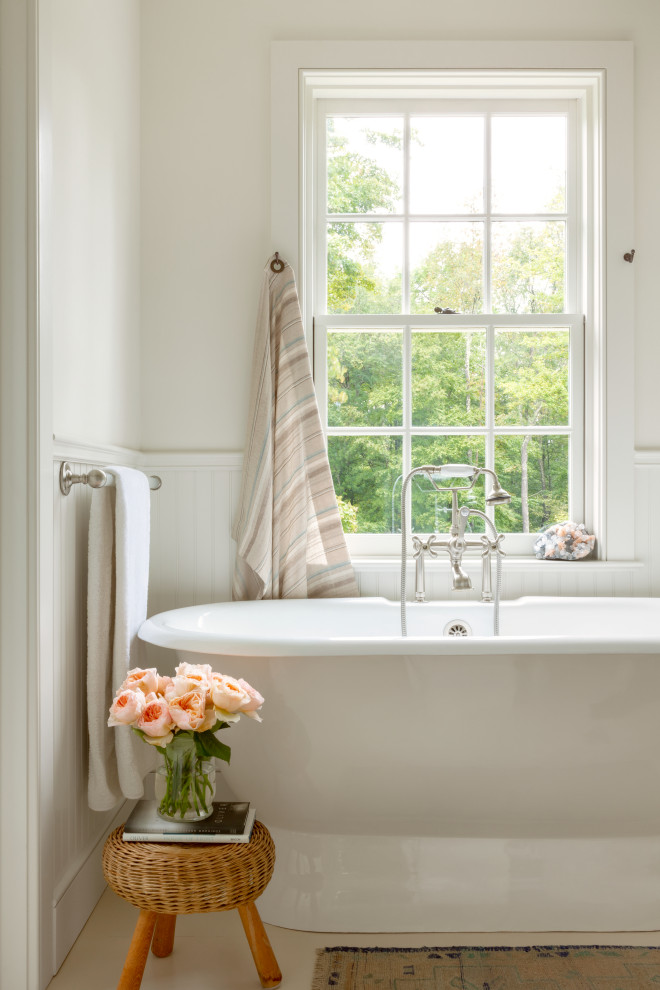 На фото: ванная комната в стиле кантри с отдельно стоящей ванной, белыми стенами и панелями на стенах