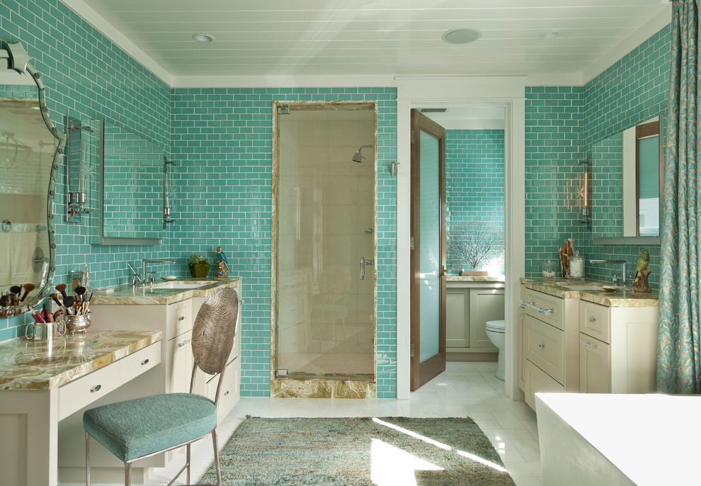 На фото: большая главная ванная комната в морском стиле с врезной раковиной, бежевыми фасадами, отдельно стоящей ванной, душем в нише, синей плиткой, плиткой кабанчик, синими стенами, фасадами в стиле шейкер, раздельным унитазом, полом из керамогранита, столешницей из оникса, белым полом, душем с распашными дверями и разноцветной столешницей