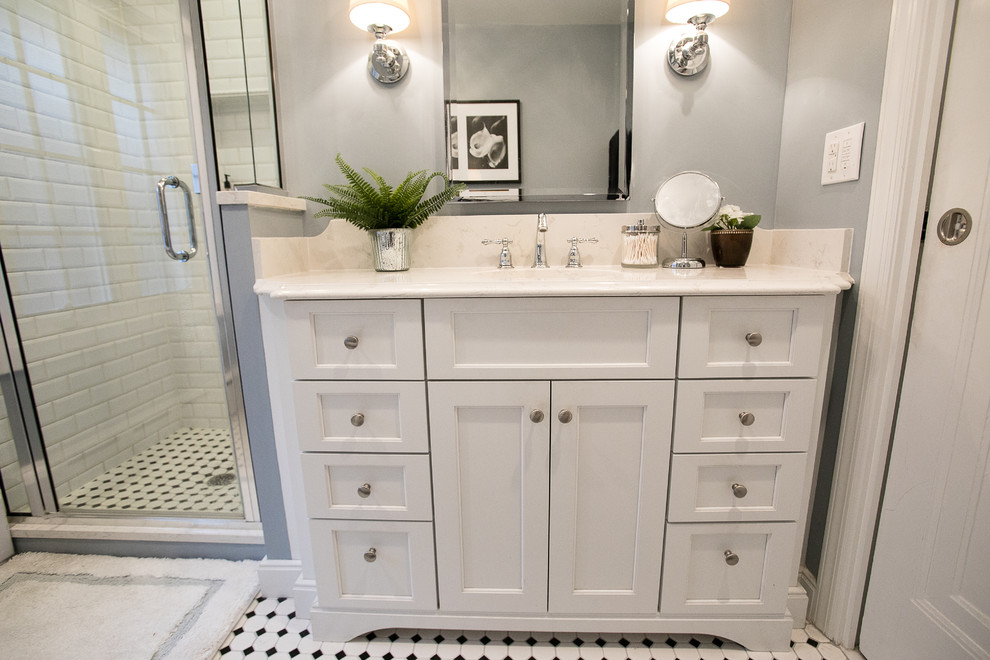 This is an example of a small classic ensuite bathroom in Other with freestanding cabinets, white cabinets, a claw-foot bath, an alcove shower, a two-piece toilet, white tiles, ceramic tiles, grey walls, ceramic flooring, a submerged sink, engineered stone worktops, multi-coloured floors and a hinged door.