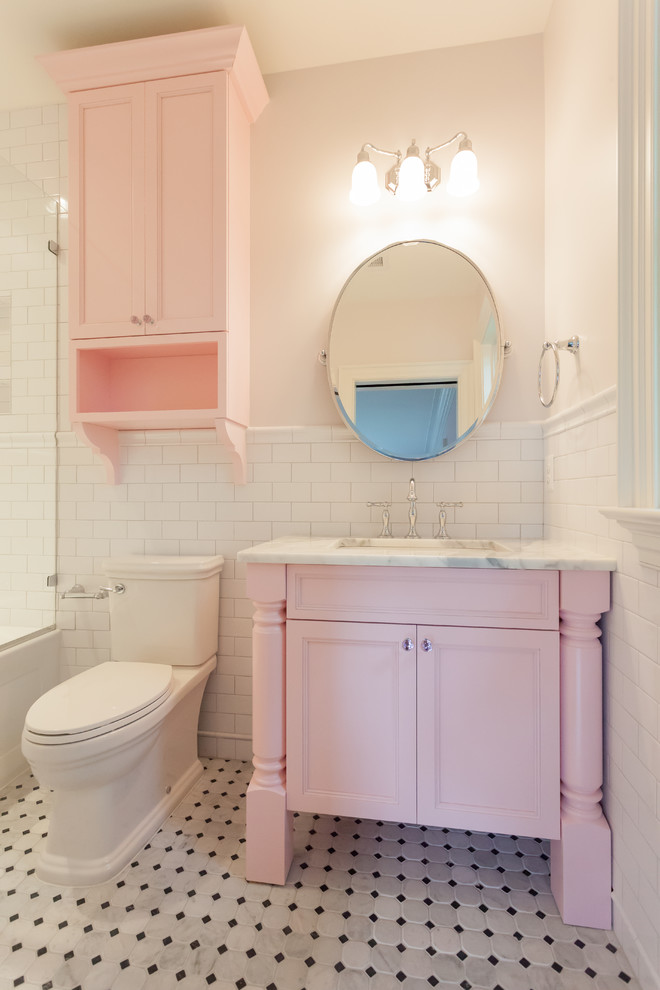 На фото: детская ванная комната в стиле кантри с фасадами островного типа, ванной в нише, душем над ванной, раздельным унитазом, белой плиткой, плиткой кабанчик, розовыми стенами, врезной раковиной, мраморной столешницей, белым полом, душем с распашными дверями и серой столешницей с