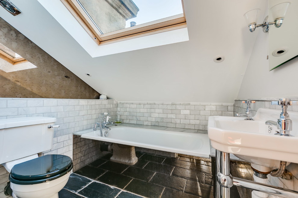 Kleines Modernes Duschbad mit weißen Fliesen, Marmorfliesen, weißer Wandfarbe, Waschtischkonsole, schwarzem Boden, Wandtoilette mit Spülkasten und Badewanne in Nische in London