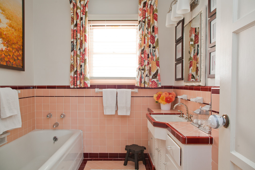 Cette image montre une salle de bain principale traditionnelle de taille moyenne avec un plan de toilette en carrelage, un plan de toilette rose, une baignoire posée, un combiné douche/baignoire et un lavabo encastré.