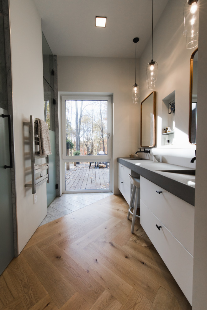 Inspiration för mellanstora moderna grått en-suite badrum, med släta luckor, vita skåp, vit kakel, vita väggar, ljust trägolv, ett integrerad handfat, bänkskiva i betong och brunt golv