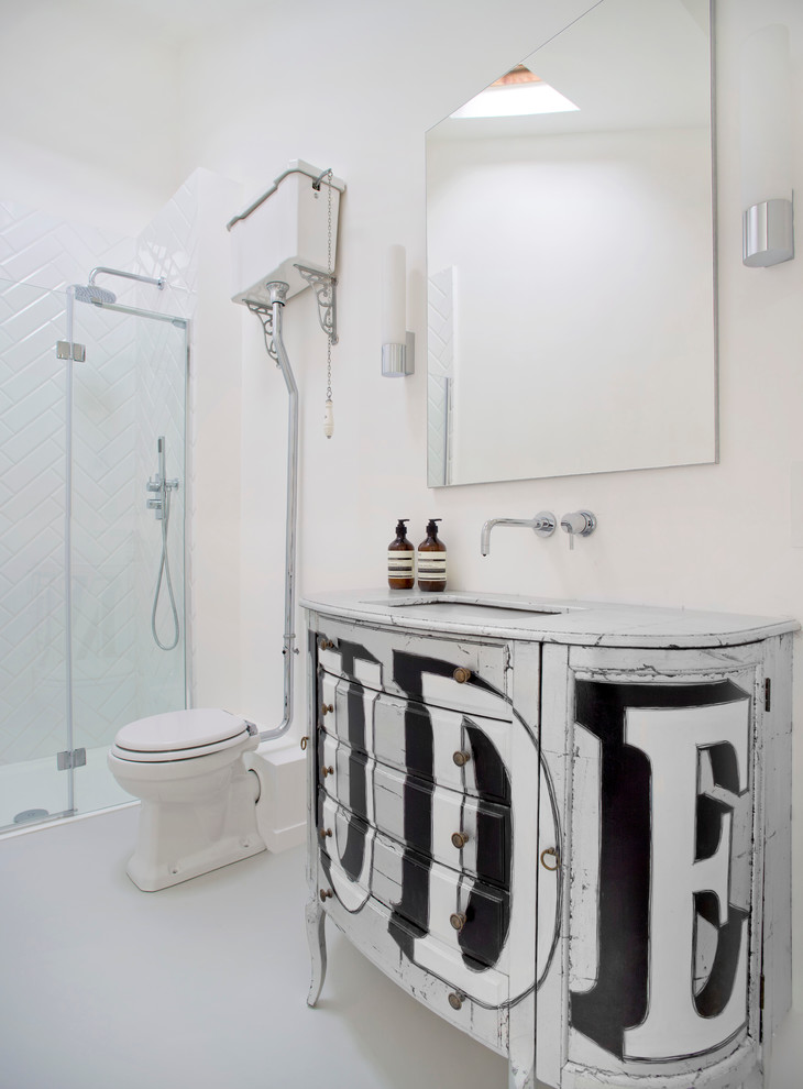 Inredning av ett eklektiskt badrum, med vita skåp, en dusch i en alkov, en toalettstol med separat cisternkåpa, vit kakel, tunnelbanekakel, vita väggar, ett undermonterad handfat, dusch med gångjärnsdörr och luckor med upphöjd panel