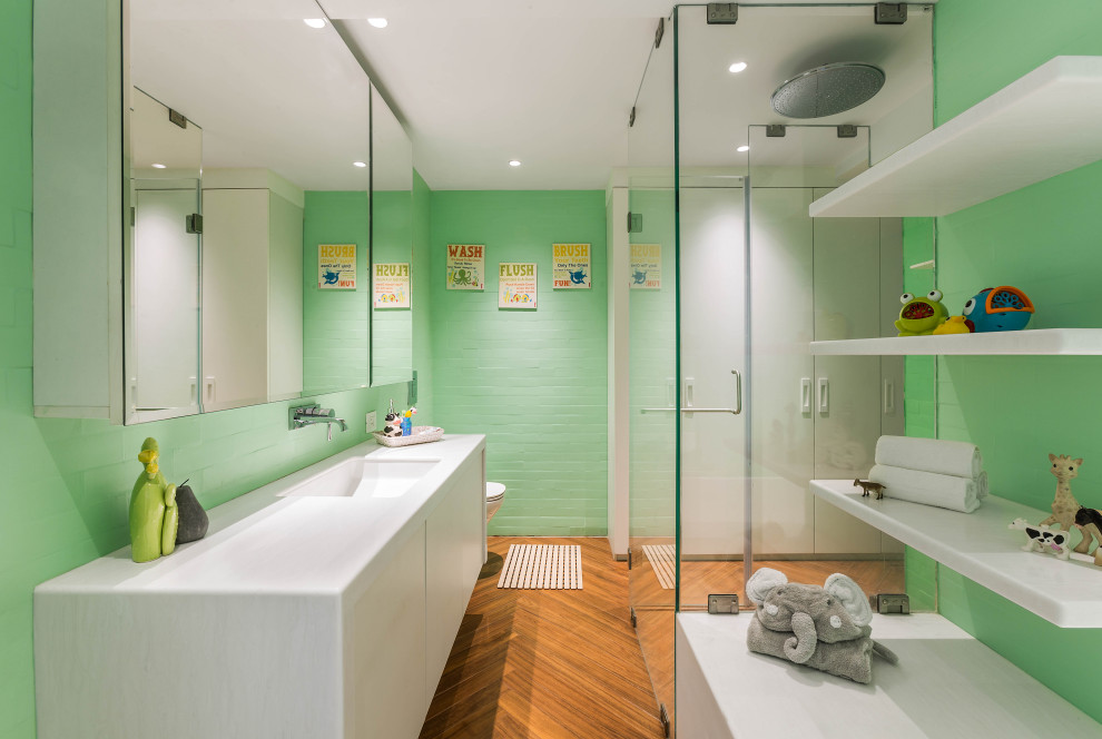 Contemporary bathroom in Mumbai with flat-panel cabinets, white cabinets, green walls, a submerged sink, brown floors and white worktops.