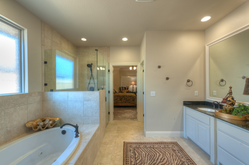 На фото: ванная комната в классическом стиле с врезной раковиной, фасадами с выступающей филенкой, белыми фасадами, столешницей из гранита, накладной ванной, угловым душем, раздельным унитазом, бежевой плиткой и керамической плиткой