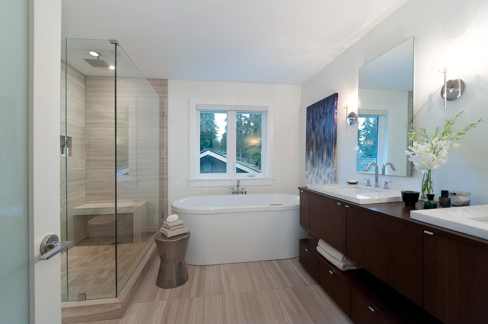 Modern inredning av ett badrum, med släta luckor, skåp i mörkt trä, träbänkskiva, ett fristående badkar och en dusch i en alkov