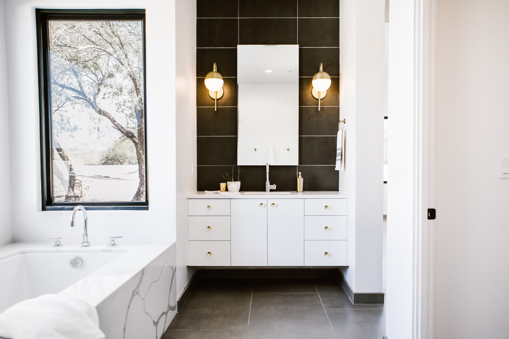Photo of a medium sized scandi ensuite bathroom in Other with flat-panel cabinets, white cabinets, an alcove bath, a corner shower, a one-piece toilet, white tiles, porcelain tiles, white walls, porcelain flooring, a submerged sink, engineered stone worktops, grey floors, a hinged door and white worktops.
