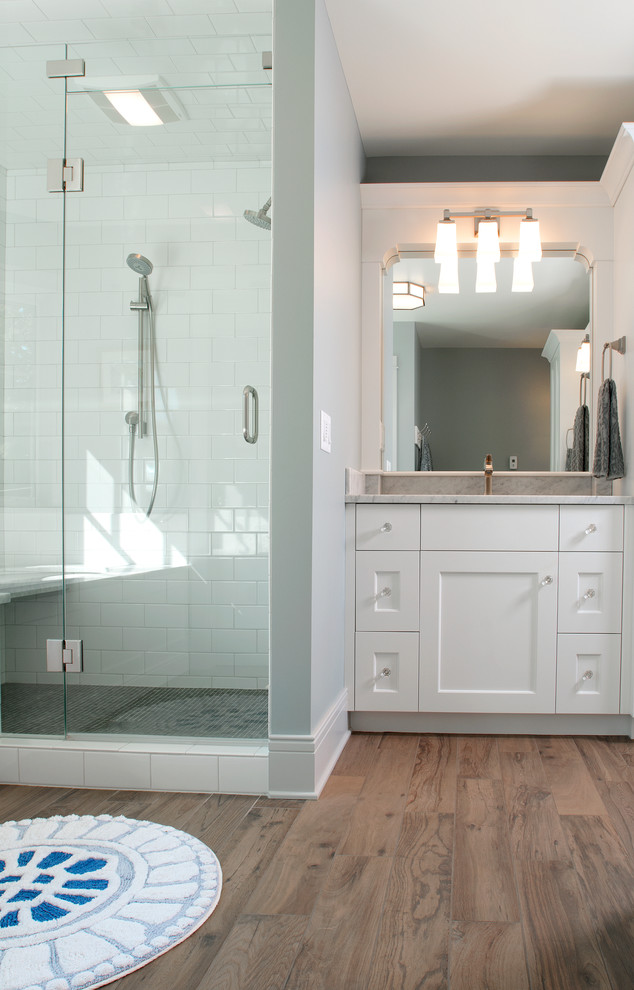 This is an example of a medium sized coastal bathroom in Grand Rapids with recessed-panel cabinets, white cabinets, granite worktops, a walk-in shower, multi-coloured tiles, mosaic tiles, blue walls and light hardwood flooring.