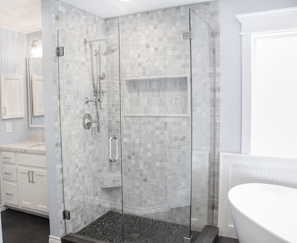 Inspiration for a medium sized traditional ensuite bathroom in Houston with raised-panel cabinets, white cabinets, a freestanding bath, a built-in shower, a two-piece toilet, grey tiles, mosaic tiles, blue walls, ceramic flooring, a submerged sink, engineered stone worktops, black floors, a hinged door and white worktops.