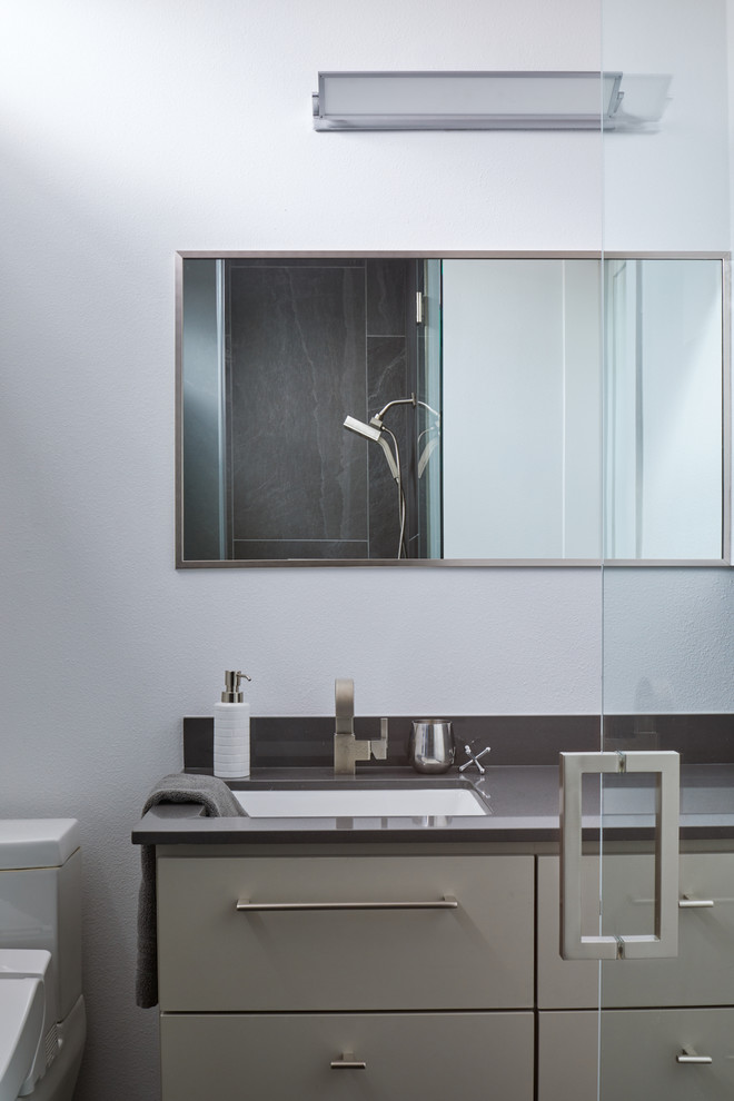 Cette photo montre une salle de bain tendance avec un placard à porte plane, des portes de placards vertess, un mur blanc, un lavabo encastré, un plan de toilette en quartz modifié et un plan de toilette gris.