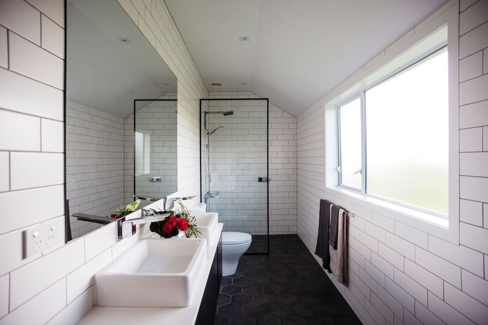 На фото: ванная комната в современном стиле с плоскими фасадами, черными фасадами, душем без бортиков, унитазом-моноблоком, белой плиткой, плиткой кабанчик, белыми стенами, душевой кабиной, настольной раковиной, черным полом, открытым душем и белой столешницей