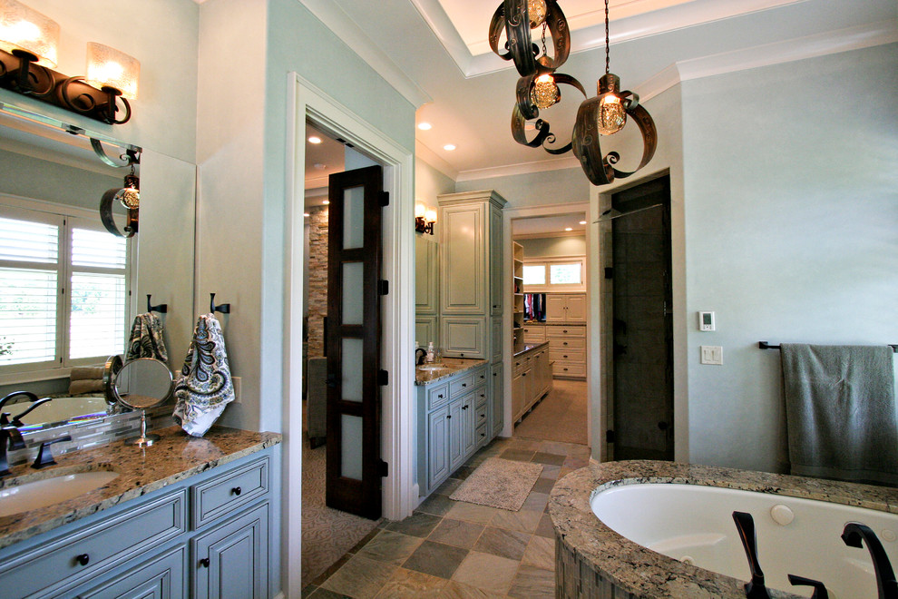 На фото: главная ванная комната в классическом стиле с врезной раковиной, столешницей из гранита, отдельно стоящей ванной, серой плиткой, синими стенами, каменной плиткой и полом из сланца