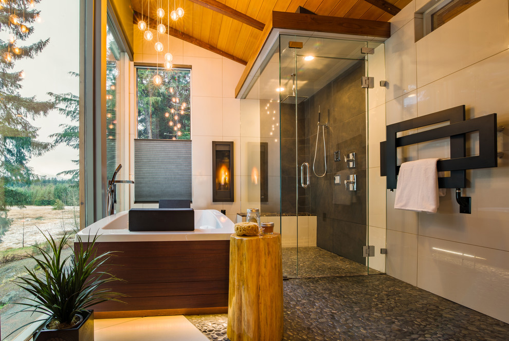 Cette image montre une très grande salle de bain principale minimaliste en bois brun avec un placard à porte plane, une baignoire indépendante, une douche ouverte, un carrelage gris, une plaque de galets, un mur gris, un sol en carrelage de porcelaine, un lavabo encastré et un plan de toilette en marbre.