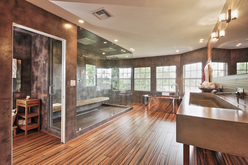 Bild på ett funkis badrum, med ett avlångt handfat, bänkskiva i betong, ett fristående badkar, en dubbeldusch och brun kakel