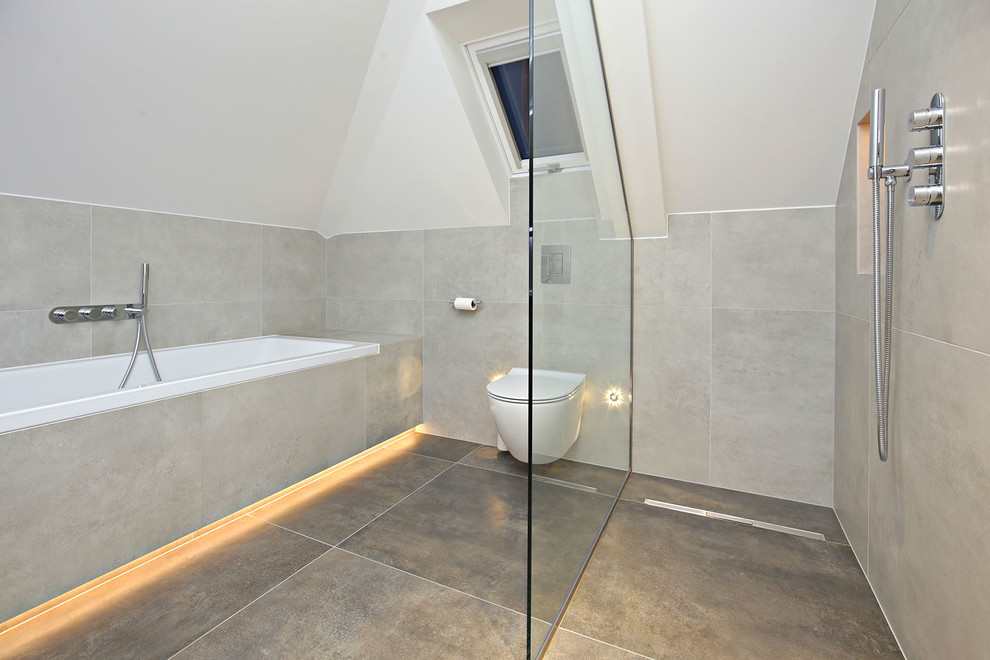Medium sized modern bathroom in London with a built-in bath, a wall mounted toilet, grey tiles, porcelain tiles, grey walls, porcelain flooring, a wall-mounted sink, grey floors and an open shower.
