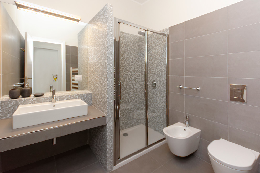Mid-sized trendy master gray tile and ceramic tile ceramic tile corner shower photo in Milan with a console sink, tile countertops, a wall-mount toilet and white walls