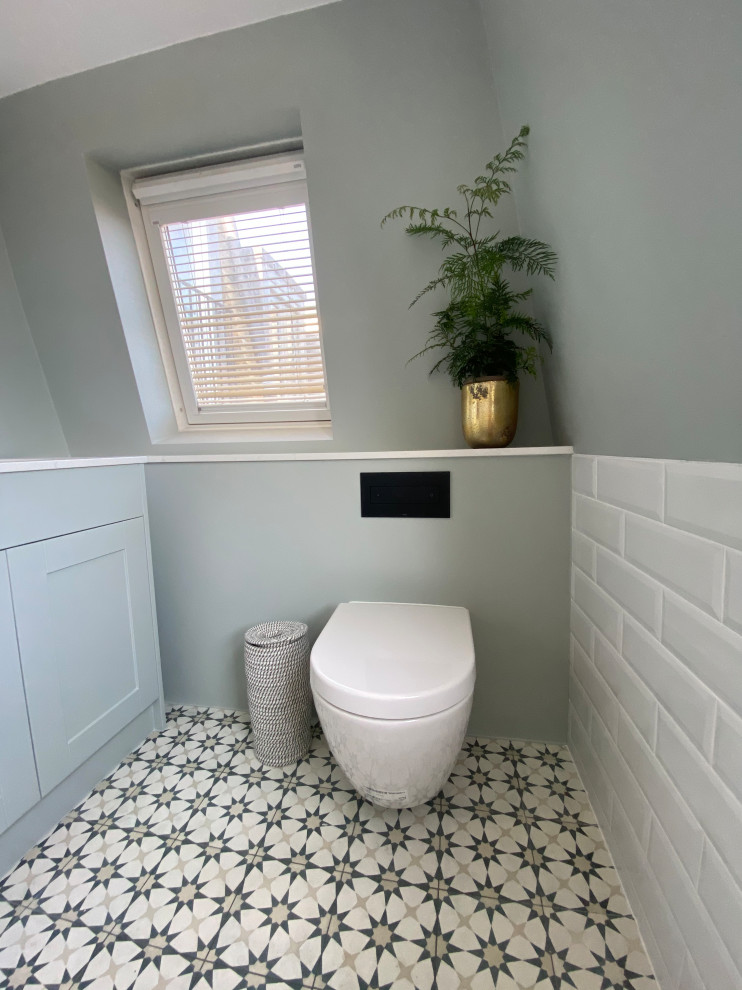 Идея дизайна: туалет среднего размера в современном стиле с фасадами в стиле шейкер, синими фасадами, инсталляцией, белой плиткой, керамической плиткой, белыми стенами, полом из керамической плитки, накладной раковиной, столешницей из кварцита, разноцветным полом, белой столешницей и встроенной тумбой