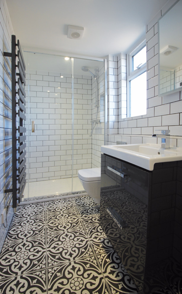 Inspiration for a small modern ensuite bathroom in Oxfordshire with flat-panel cabinets, black cabinets, a corner shower, a wall mounted toilet, ceramic tiles, white walls, ceramic flooring, a wall-mounted sink, multi-coloured floors and a sliding door.