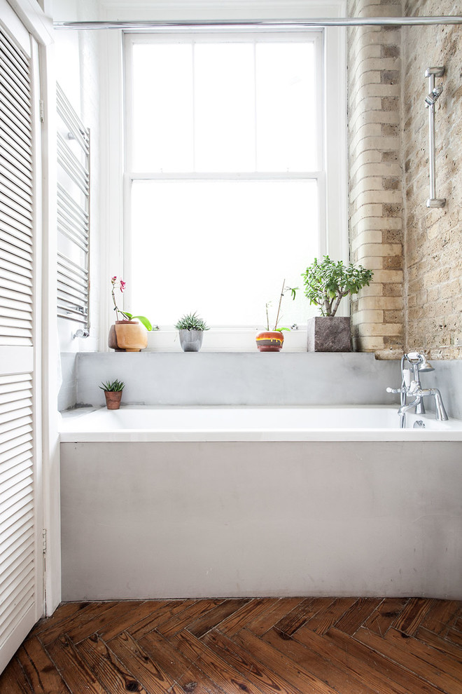 Ejemplo de cuarto de baño contemporáneo con bañera empotrada, suelo de madera en tonos medios y piedra