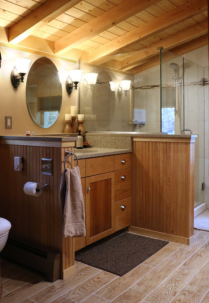Modelo de cuarto de baño principal rústico de tamaño medio con armarios con paneles lisos, puertas de armario de madera clara, ducha esquinera, sanitario de una pieza y paredes beige