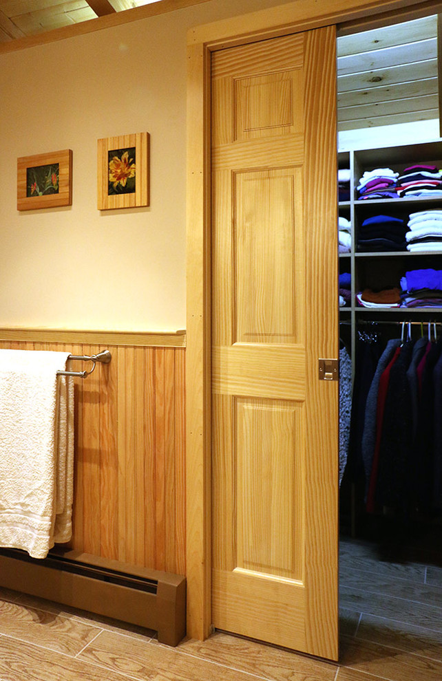 Cette image montre une salle de bain principale chalet en bois clair de taille moyenne avec un placard à porte plane, une douche d'angle, WC à poser et parquet clair.