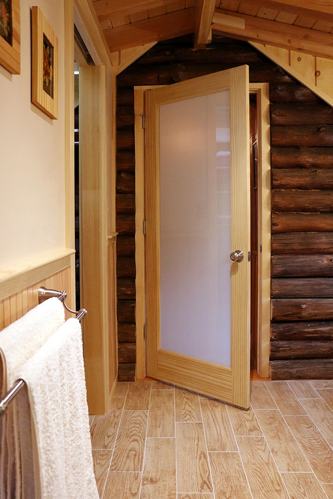 Ejemplo de cuarto de baño principal rural de tamaño medio con armarios con paneles lisos, puertas de armario de madera clara, ducha esquinera y sanitario de una pieza