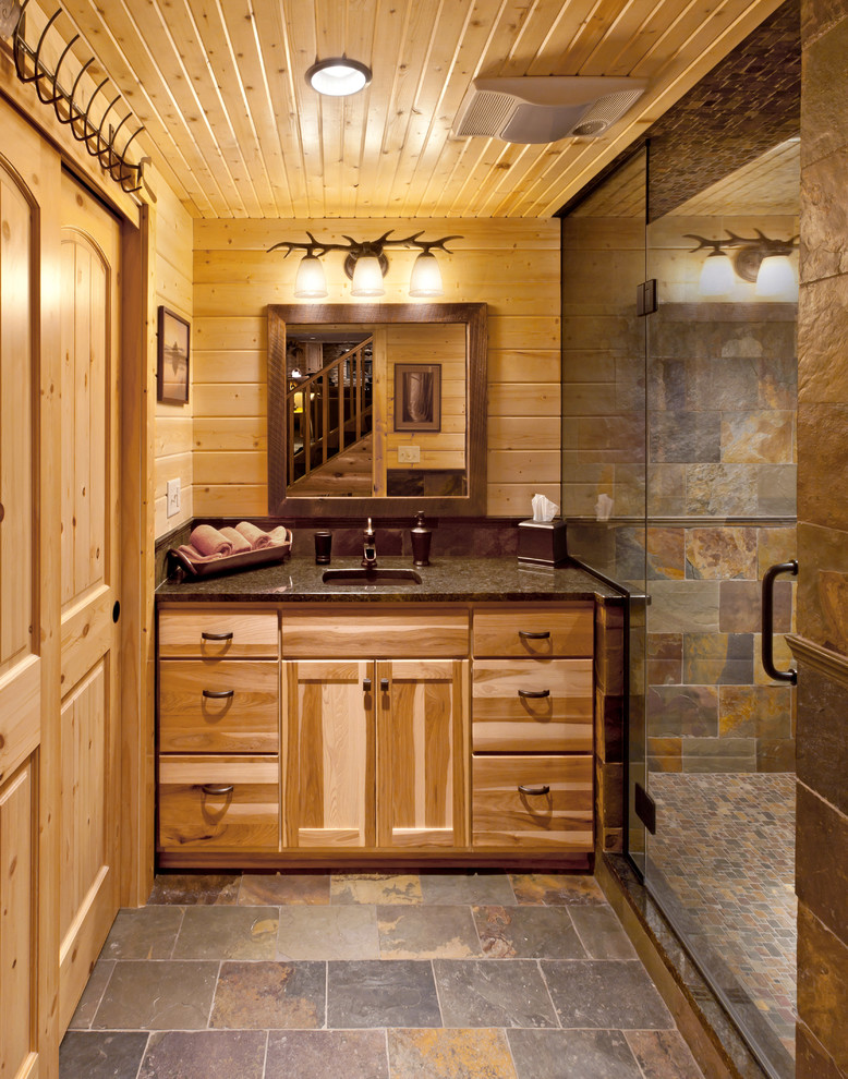 Idées déco pour une douche en alcôve montagne en bois brun avec un lavabo encastré, un placard à porte plane et un carrelage de pierre.