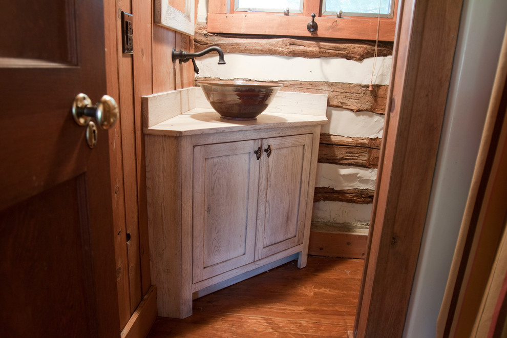 This is an example of a small farmhouse bathroom in DC Metro with a vessel sink, flat-panel cabinets, distressed cabinets and wooden worktops.