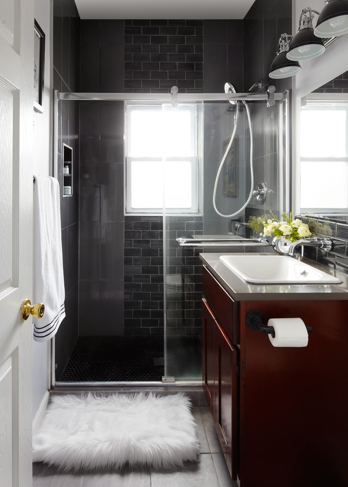 Example of an urban black tile and glass tile porcelain tile doorless shower design in Chicago with furniture-like cabinets, dark wood cabinets, a two-piece toilet, gray walls, a drop-in sink and concrete countertops