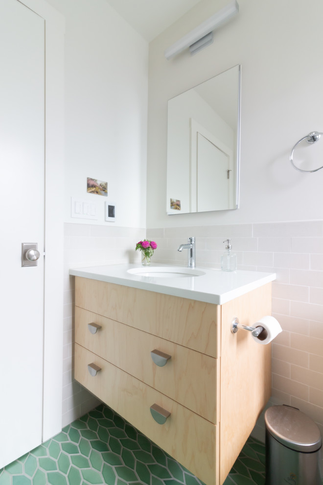Стильный дизайн: ванная комната в скандинавском стиле с плоскими фасадами, светлыми деревянными фасадами, ванной в нише, душем над ванной, раздельным унитазом, бежевой плиткой, керамогранитной плиткой, белыми стенами, полом из керамической плитки, душевой кабиной, врезной раковиной, столешницей из искусственного кварца, зеленым полом, шторкой для ванной и белой столешницей - последний тренд
