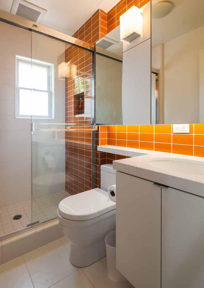Immagine di una stanza da bagno design con doccia alcova e piastrelle arancioni