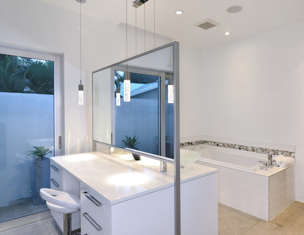 Bathroom - mid-sized contemporary master white tile concrete floor bathroom idea in Tampa with a vessel sink, white cabinets, quartzite countertops and white walls