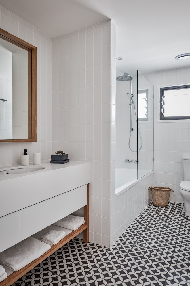 Пример оригинального дизайна: ванная комната в морском стиле с плоскими фасадами, белыми фасадами, ванной в нише, душем над ванной, белой плиткой, плиткой кабанчик, белыми стенами, полом из цементной плитки, душевой кабиной, черным полом, белой столешницей и врезной раковиной