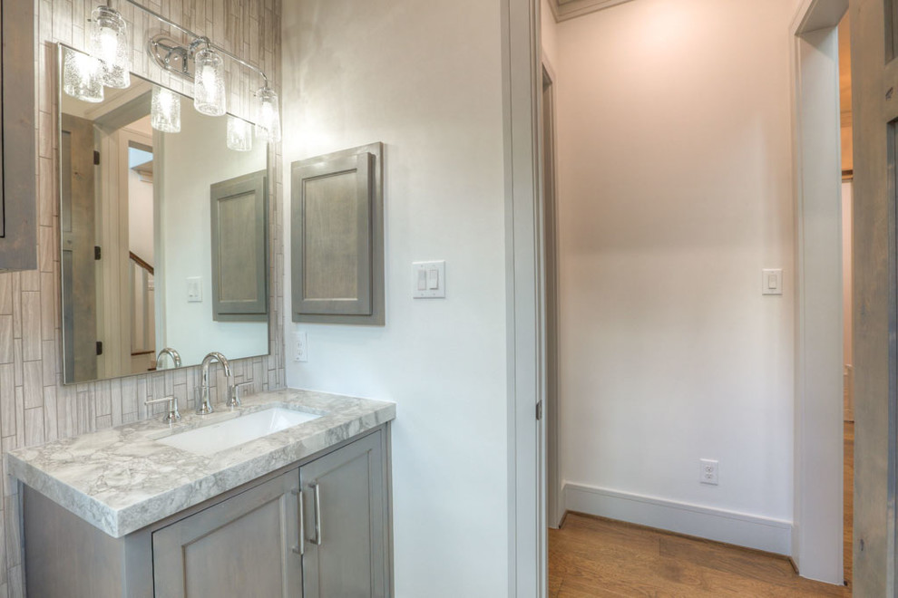 Inspiration for a mid-sized craftsman 3/4 white tile and porcelain tile beige floor alcove shower remodel in Houston with recessed-panel cabinets, light wood cabinets, a two-piece toilet, beige walls, an undermount sink, granite countertops and a hinged shower door