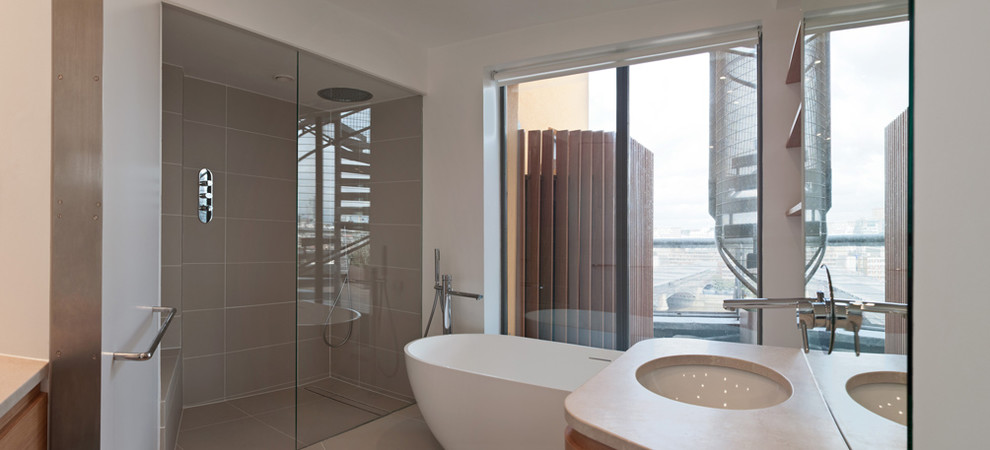 Idéer för ett modernt badrum, med ett fristående badkar, en dubbeldusch, luckor med infälld panel, bänkskiva i kalksten och beige kakel